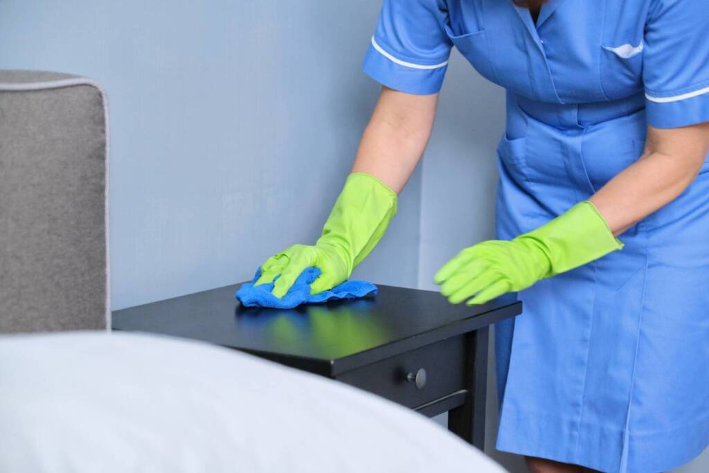 Cleaning service, woman in uniform with gloves with rag clean room